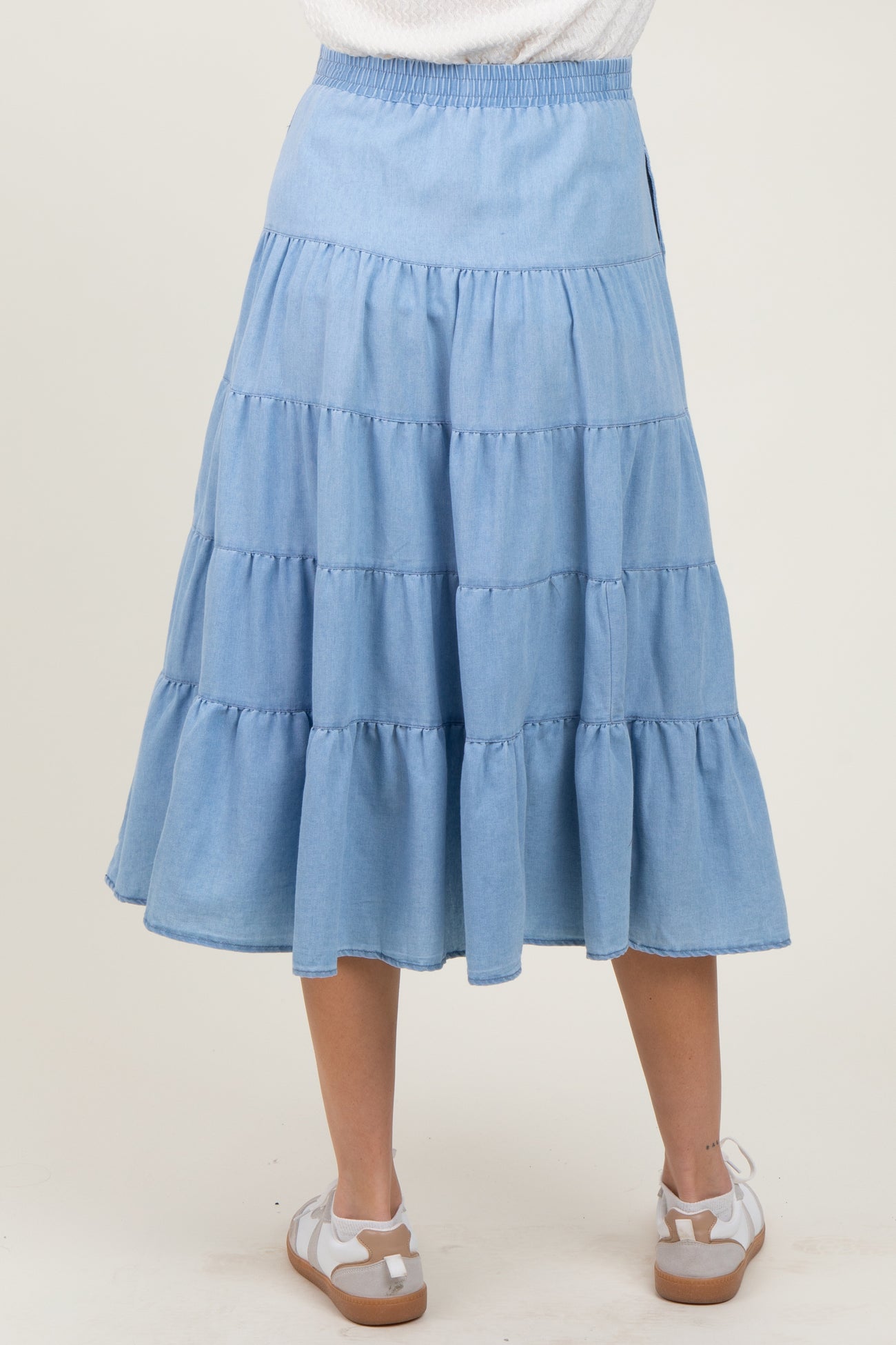 woman wearing a light blue tiered maternity skirt with an elastic waistband, viewed from the back
