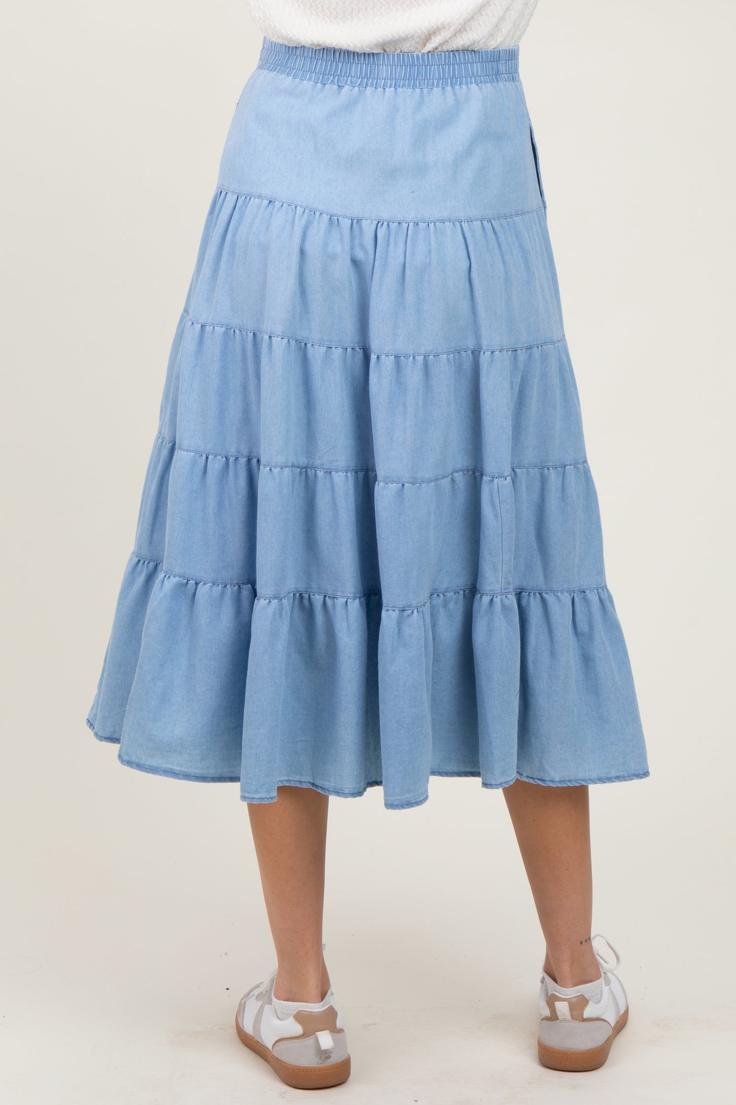 woman wearing a light blue tiered maternity skirt with an elastic waistband, viewed from the back