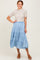 woman wearing a beige ribbed short sleeve top and a tiered light blue maxi skirt with brown heeled sandals