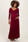 woman wearing a burgundy long sleeve maternity maxi dress and holding her baby bump