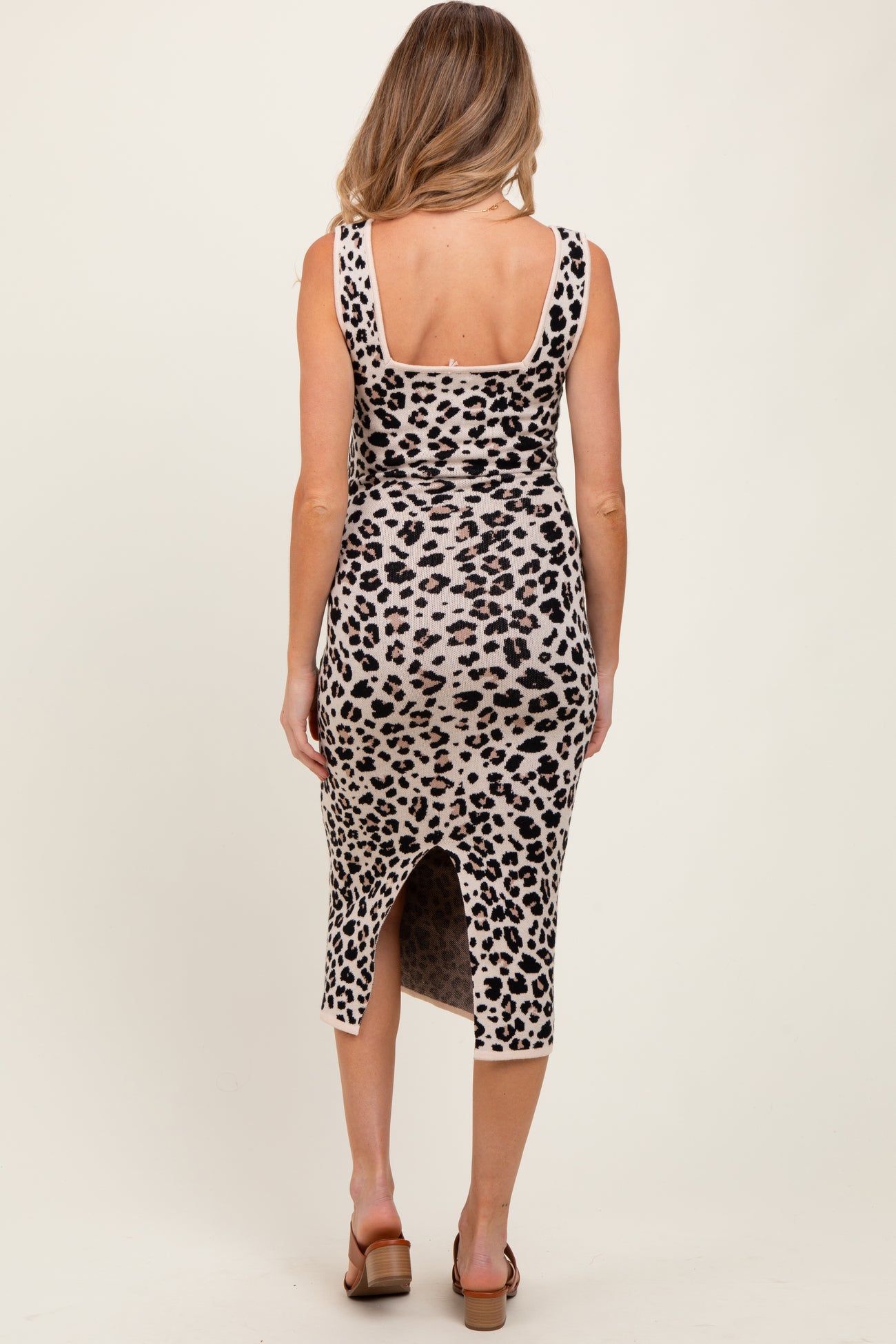 woman wearing a leopard print maternity dress with a back slit and fitted silhouette