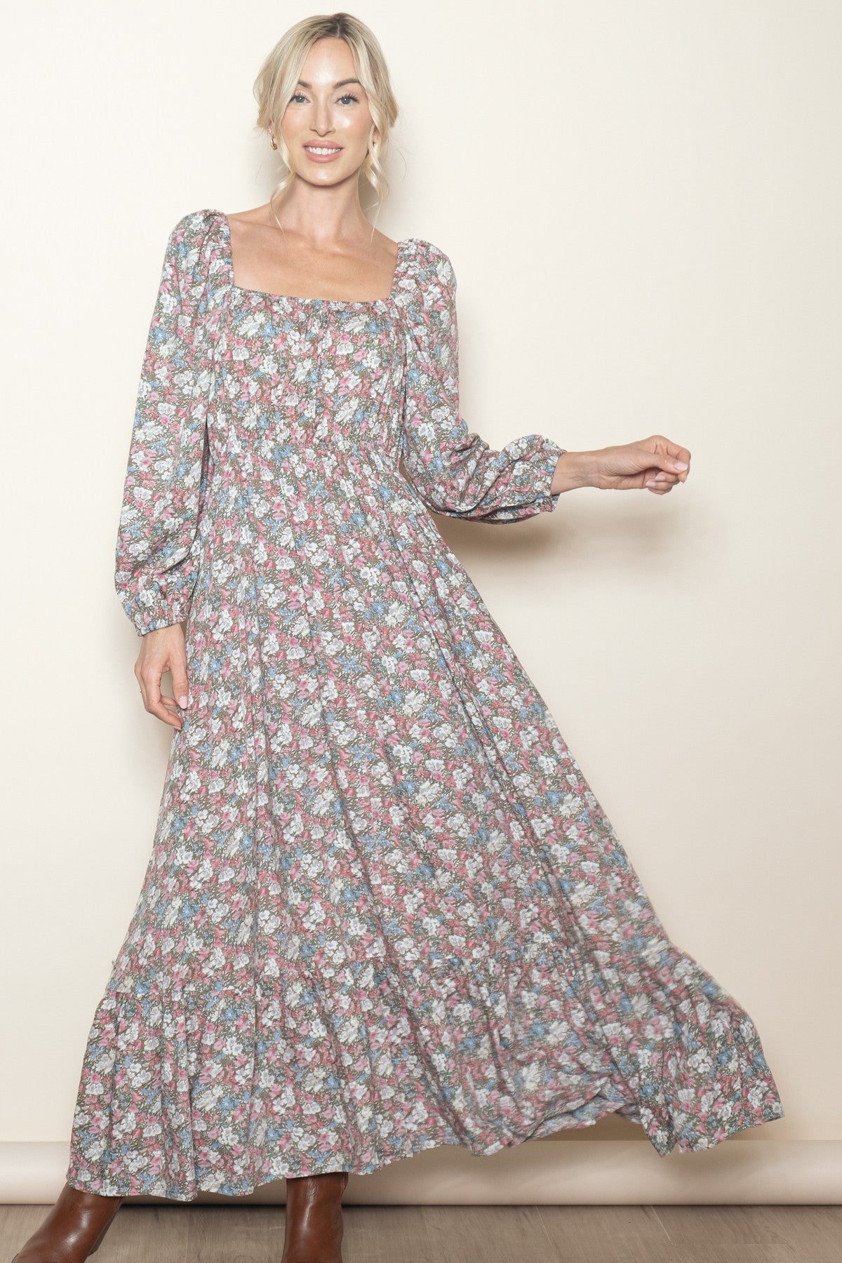 woman wearing a long floral maxi dress with puff sleeves and a square neckline, smiling against a light background