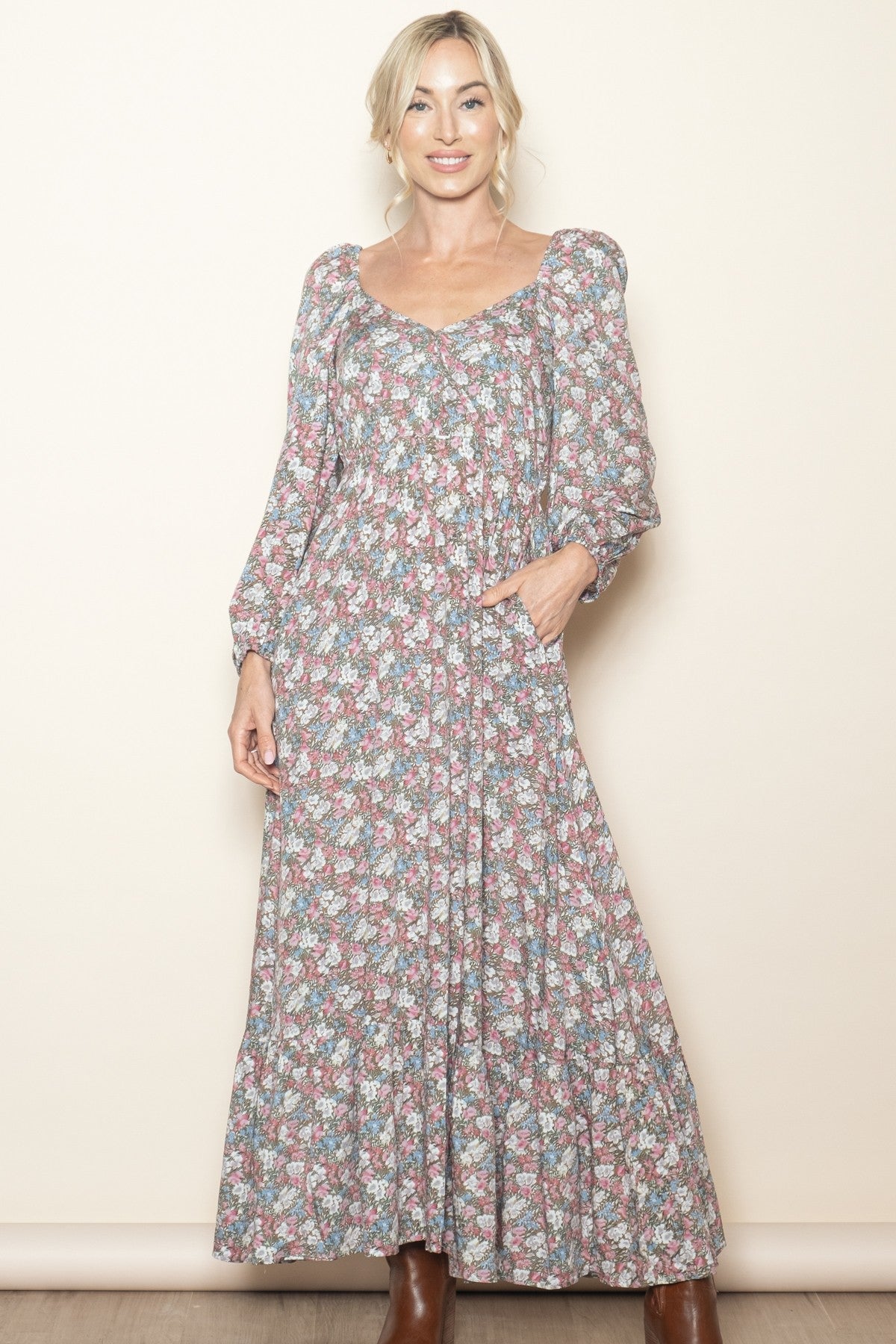woman wearing a long sleeve floral maxi dress with a gathered bodice and pockets, styled with brown boots