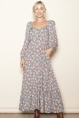 woman wearing a long sleeve floral maxi dress with a gathered bodice and pockets, styled with brown boots