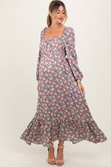 woman wearing a floral long sleeve maternity maxi dress with a square neckline and ruffled hem, showcasing her baby bump