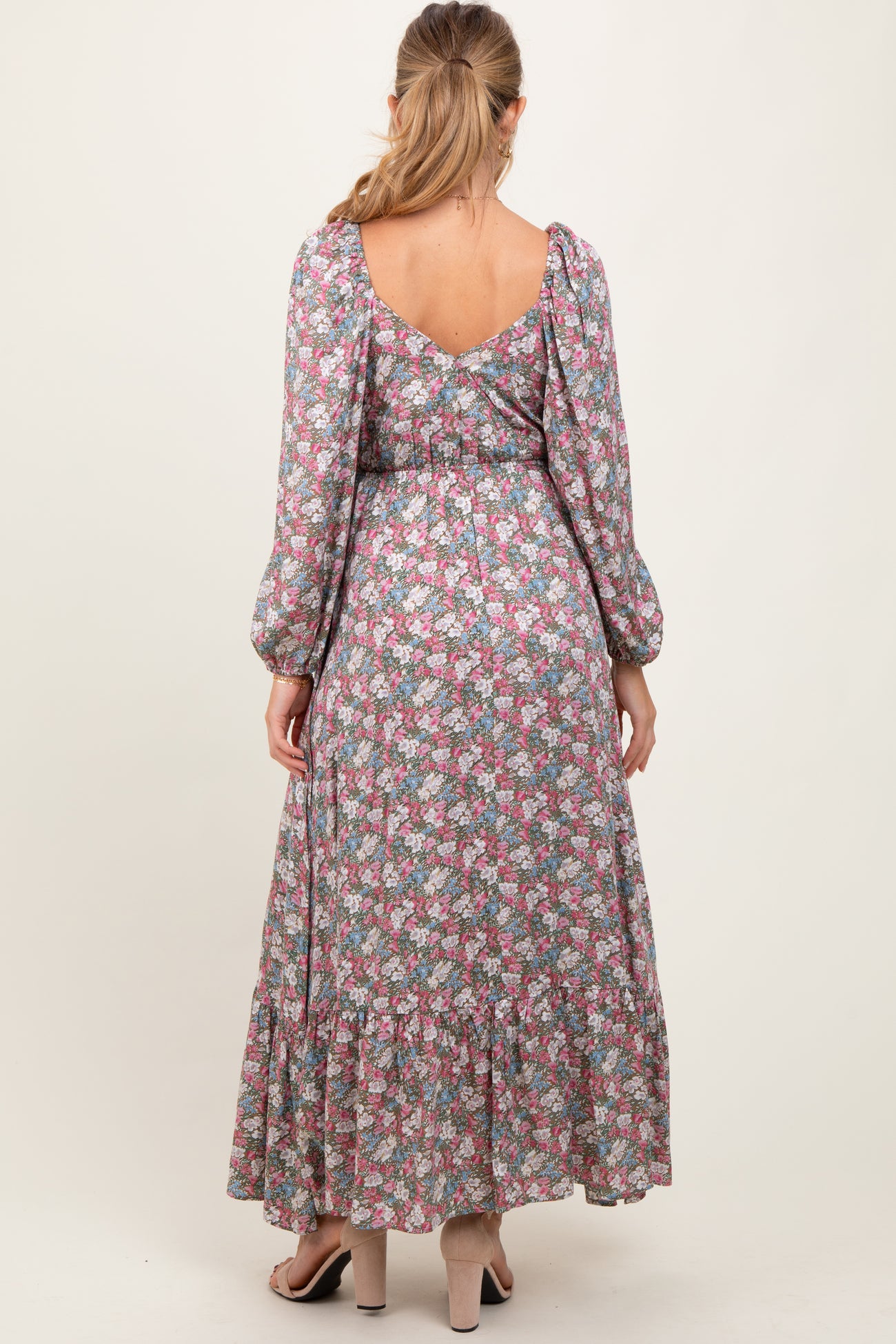 woman wearing a floral maternity maxi dress with puff sleeves and a tiered skirt, showcasing a visible baby bump