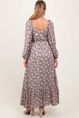 woman wearing a floral maternity maxi dress with puff sleeves and a tiered skirt, showcasing a visible baby bump