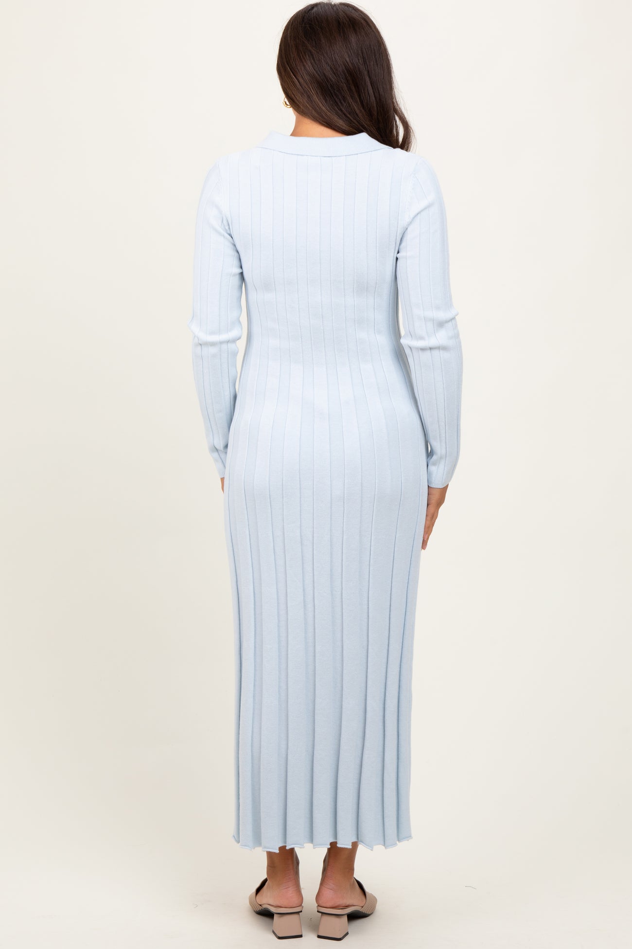 woman wearing a light blue ribbed long sleeve maternity dress, showing a fitted silhouette from the back