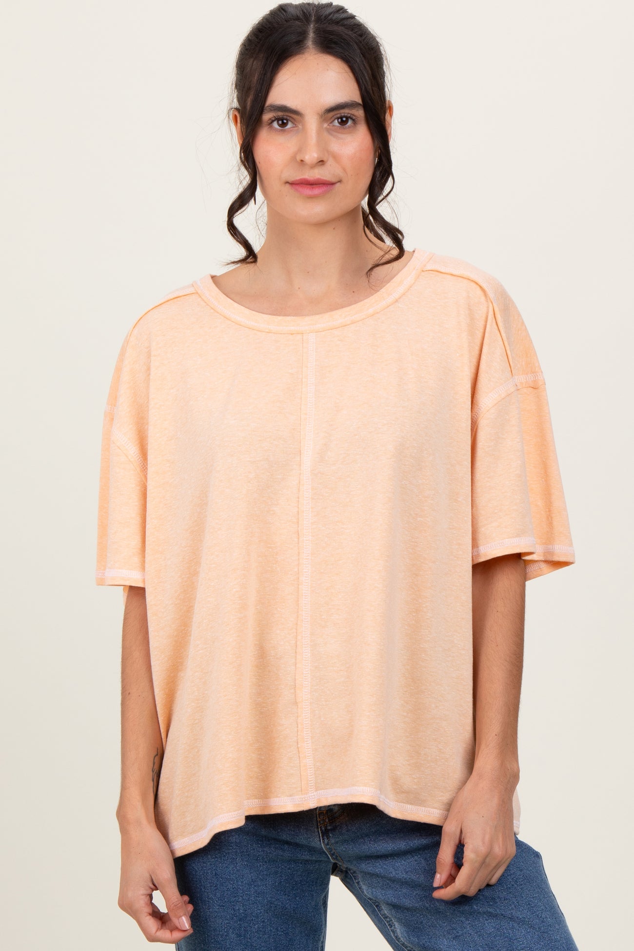 woman wearing a loose-fitting peach oversized t-shirt paired with blue jeans