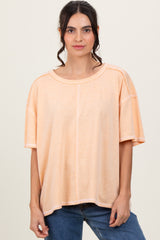 woman wearing a loose-fitting peach oversized t-shirt paired with blue jeans