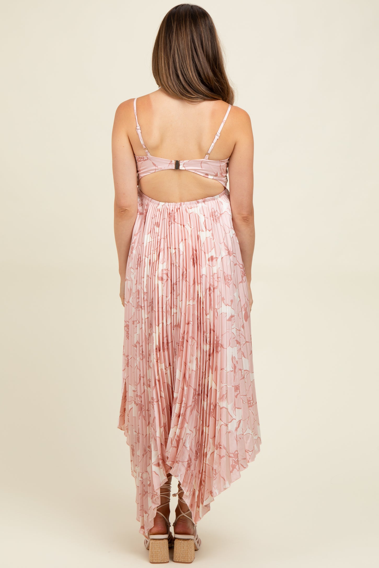 woman wearing a pink floral maternity dress with a pleated back and a high-low hemline