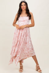 woman wearing a pink floral print sleeveless dress with an asymmetrical hem and a flowing silhouette