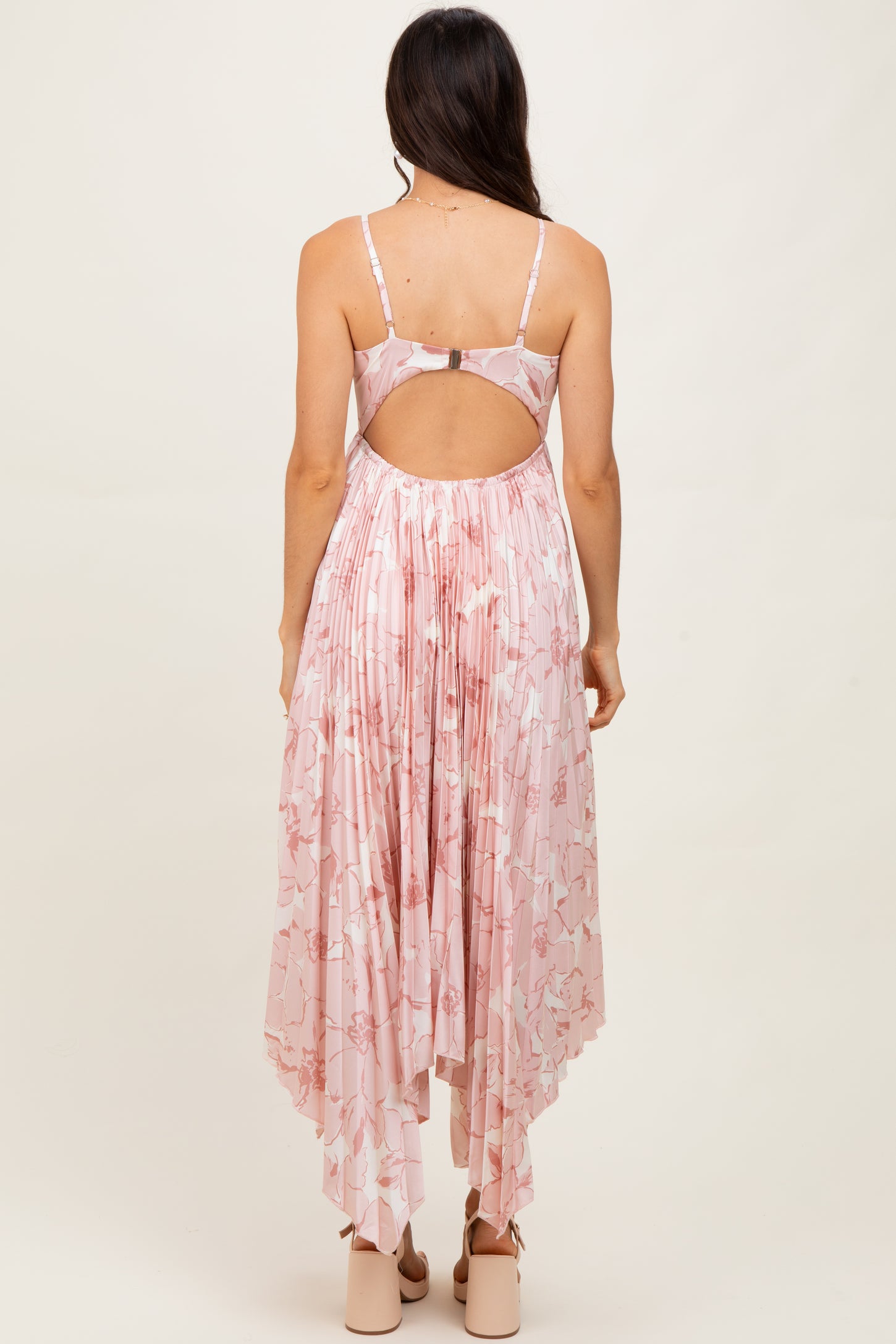 woman wearing a pink floral maxi dress with a high-low hem and open back detail