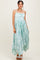 woman wearing a light blue floral print maxi dress with a flowy asymmetric hem and spaghetti straps