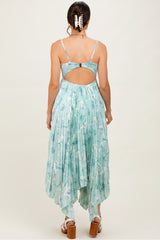 woman wearing a light blue floral print maxi dress with a cutout back and pleated design, standing with her back to the camera