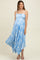 woman wearing a light blue floral maternity dress with a pleated skirt and spaghetti straps, showcasing her baby bump