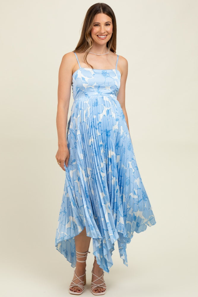 woman wearing a blue floral print maternity dress with a flowy hem and spaghetti straps, showcasing her baby bump