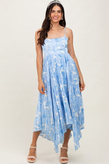 woman wearing a light blue floral print maxi dress with a high-low hem and spaghetti straps