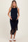 woman wearing a navy blue fringe maternity dress, showing her baby bump while standing confidently