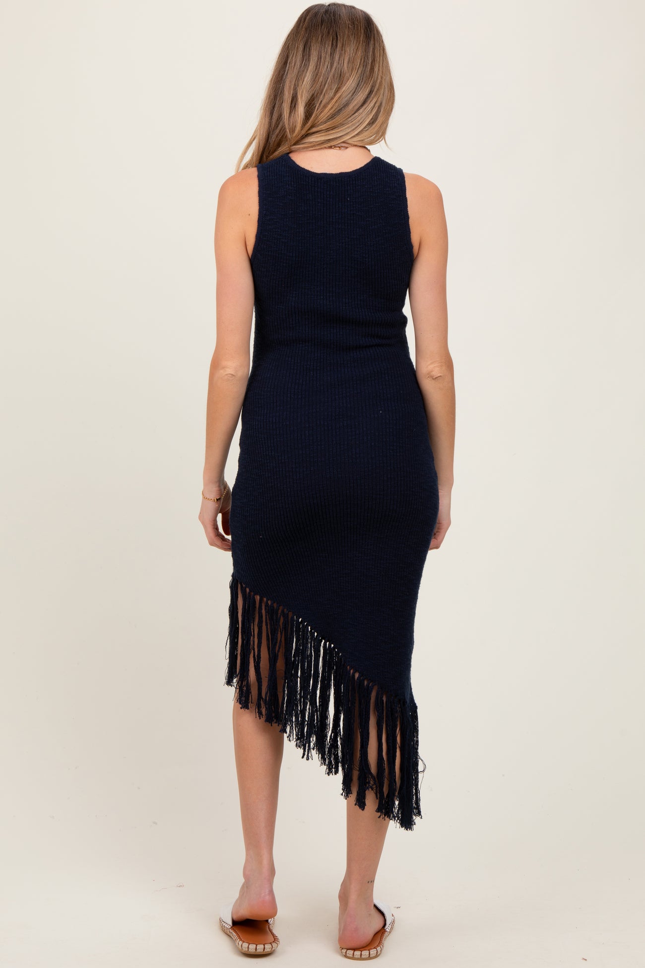 woman wearing a navy blue sleeveless maternity dress with fringe hem, showing her baby bump from the back