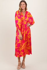 woman wearing a vibrant pink and yellow floral midi dress with a v-neckline and three-quarter sleeves