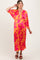 woman wearing a vibrant yellow and pink floral maternity dress with a deep v-neck and flowing sleeves, styled with brown heels