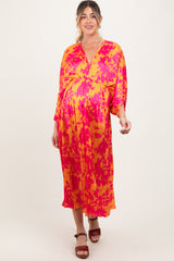 woman wearing a vibrant pink and orange patterned maternity dress with a v-neckline and three-quarter sleeves, displaying a baby bump