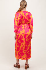 woman wearing a vibrant pink and yellow floral print maternity dress with long sleeves and a cinched waist, back view