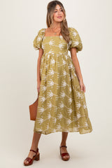 woman wearing a yellow floral maternity dress with puff sleeves and a square neckline, holding a brown bag