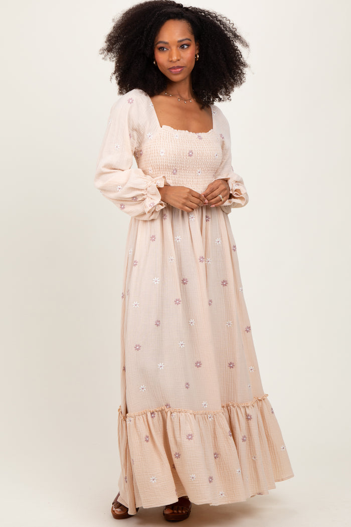 woman wearing a light pink maxi dress with floral embroidery and puff sleeves