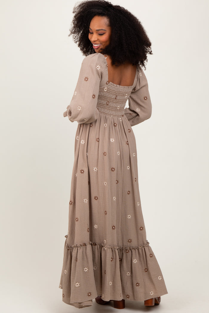 woman wearing a long brown floral embroidered maxi dress with puff sleeves and a tiered hem, showing the back view