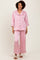 woman wearing a light pink satin pajama set with button-up top and wide-leg pants, standing and smiling