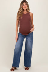woman wearing a brown ribbed maternity tank top and light blue wide-leg jeans, showing her baby bump