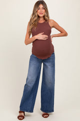 woman wearing a brown ribbed maternity tank top and wide-leg blue jeans, holding her baby bump