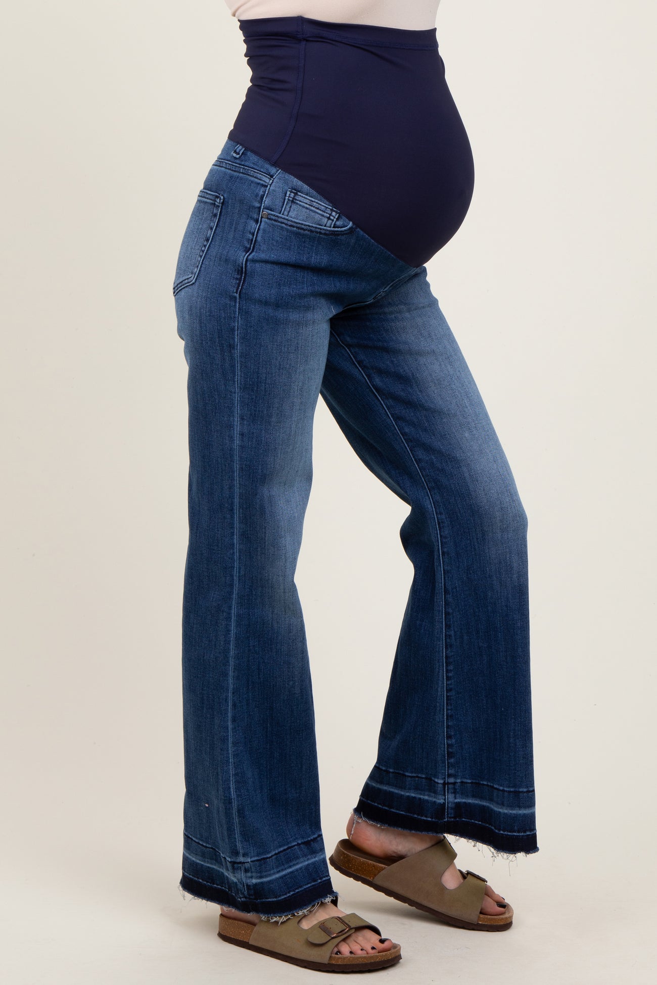 woman wearing dark blue maternity jeans with a navy high waist panel and open hem in a relaxed fit, showcasing a baby bump