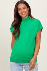 woman wearing a bright green short sleeve maternity top with a high neckline and relaxed fit, showing her baby bump