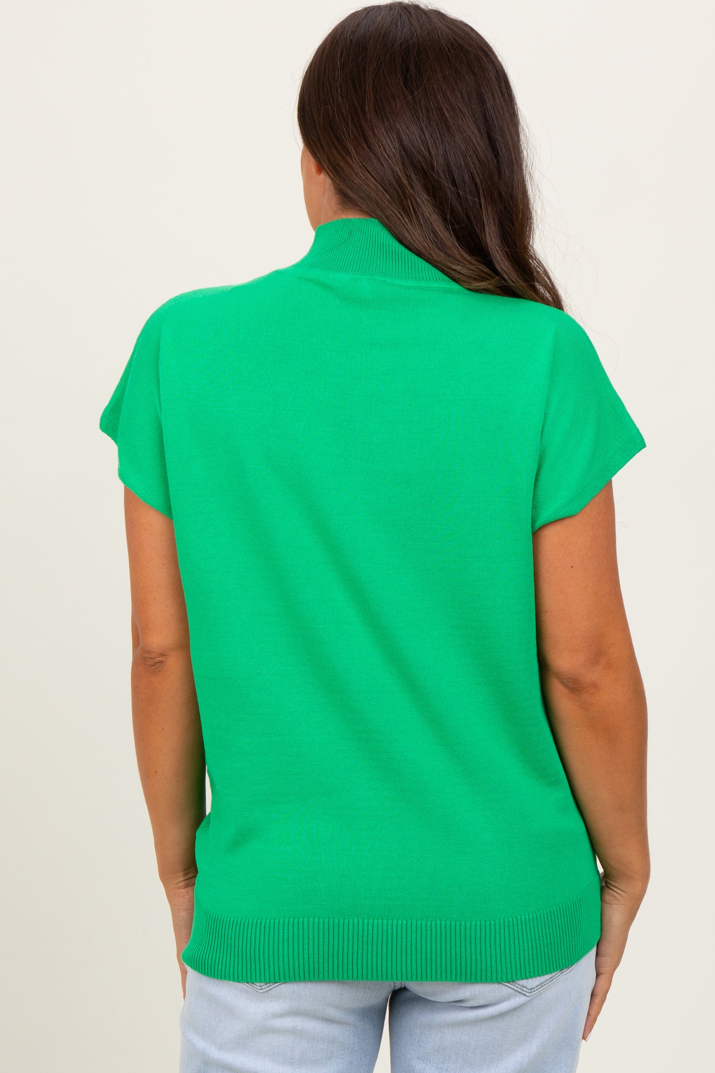 woman wearing a bright green short sleeve maternity top, showing the back view