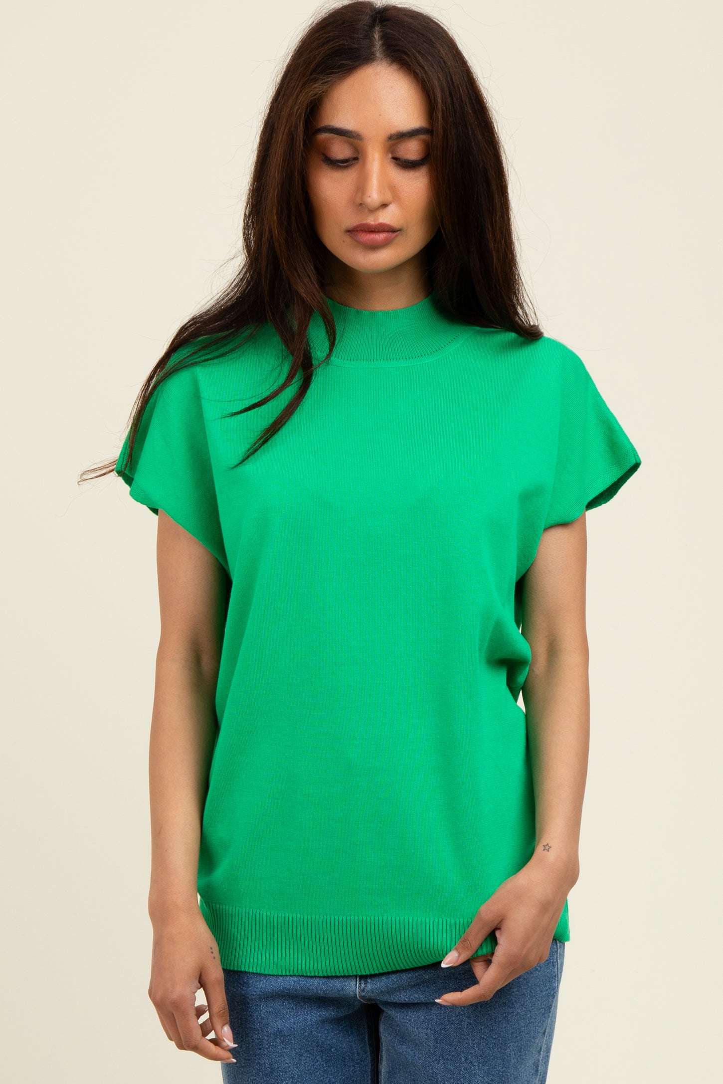 woman wearing a bright green short sleeve top with a high neckline and relaxed fit