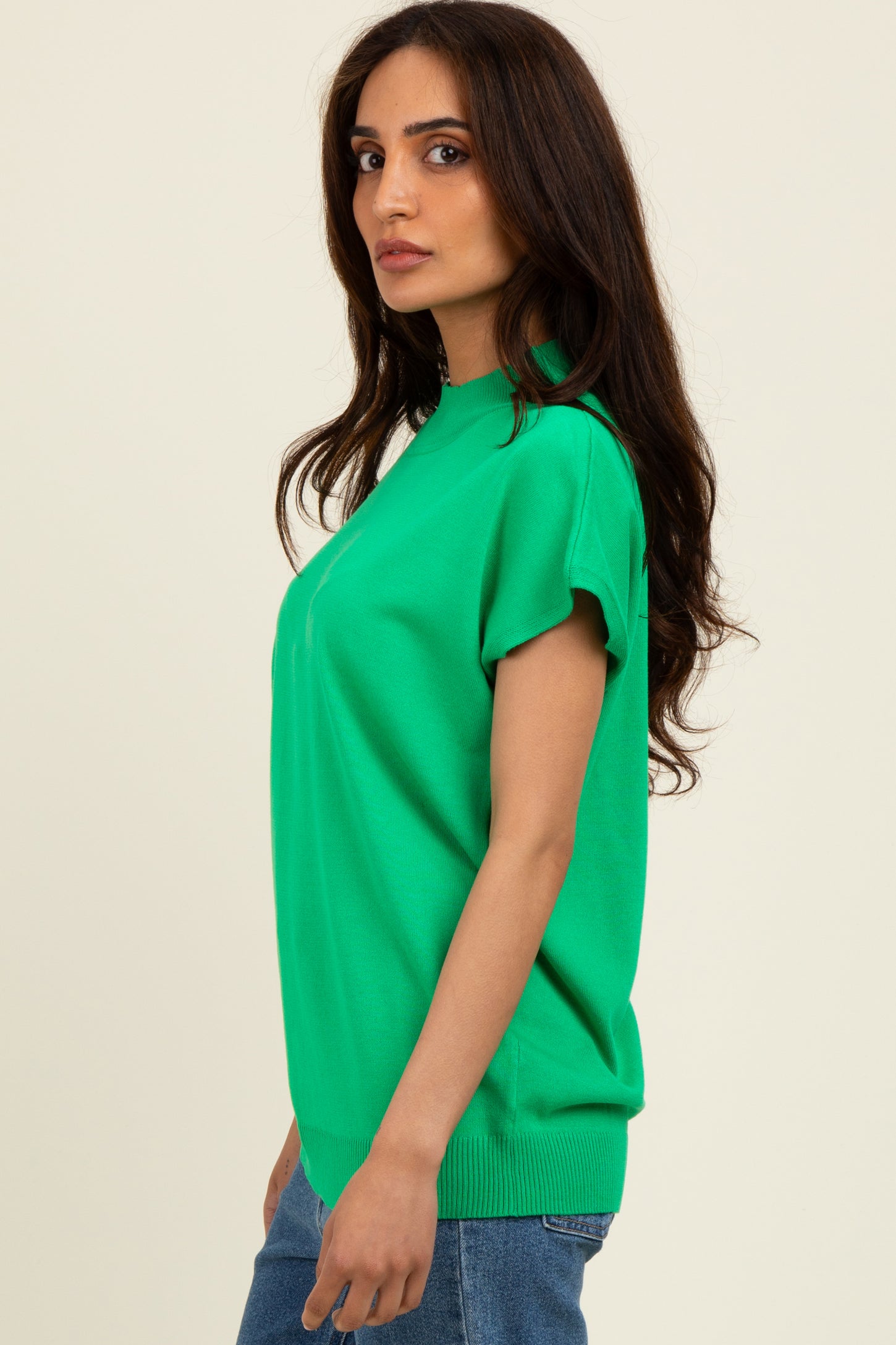 woman wearing a vibrant green short sleeve sweater with a relaxed fit and ribbed hem