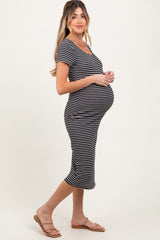 woman wearing a black and white striped maternity dress, showing her baby bump while standing sideways