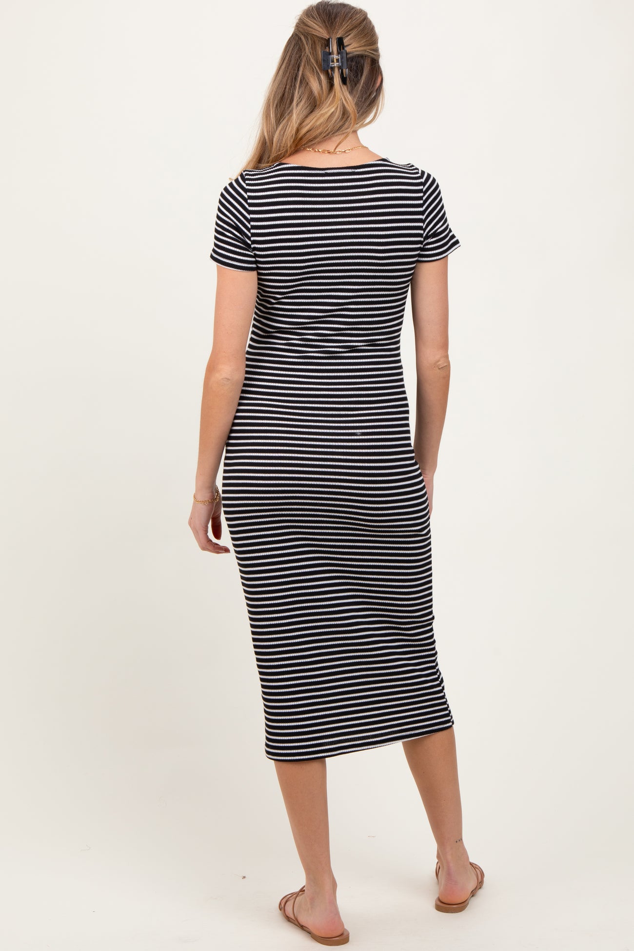 woman wearing a black and white striped maternity midi dress, shown from the back