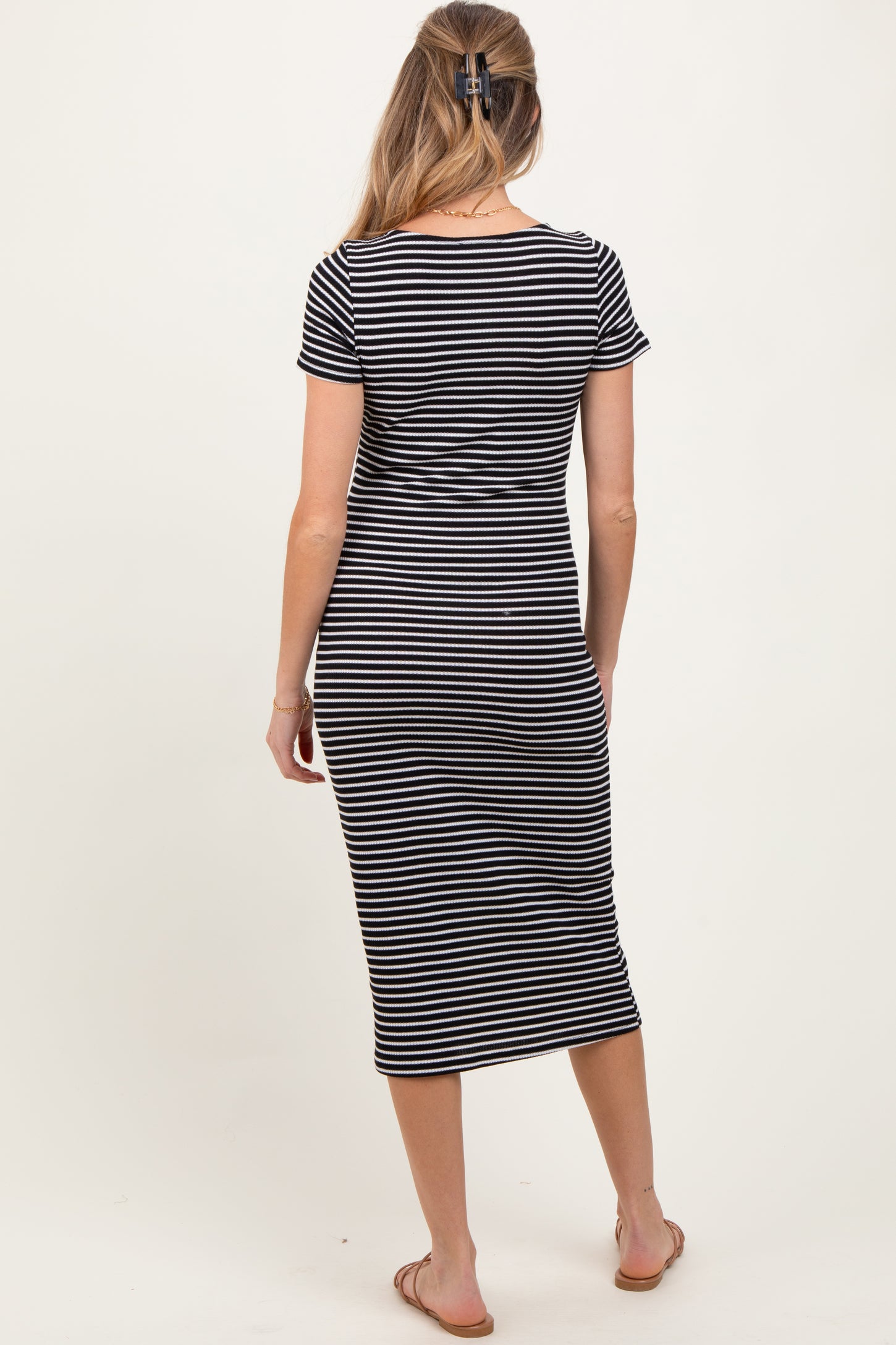 woman wearing a black and white striped maternity midi dress, shown from the back