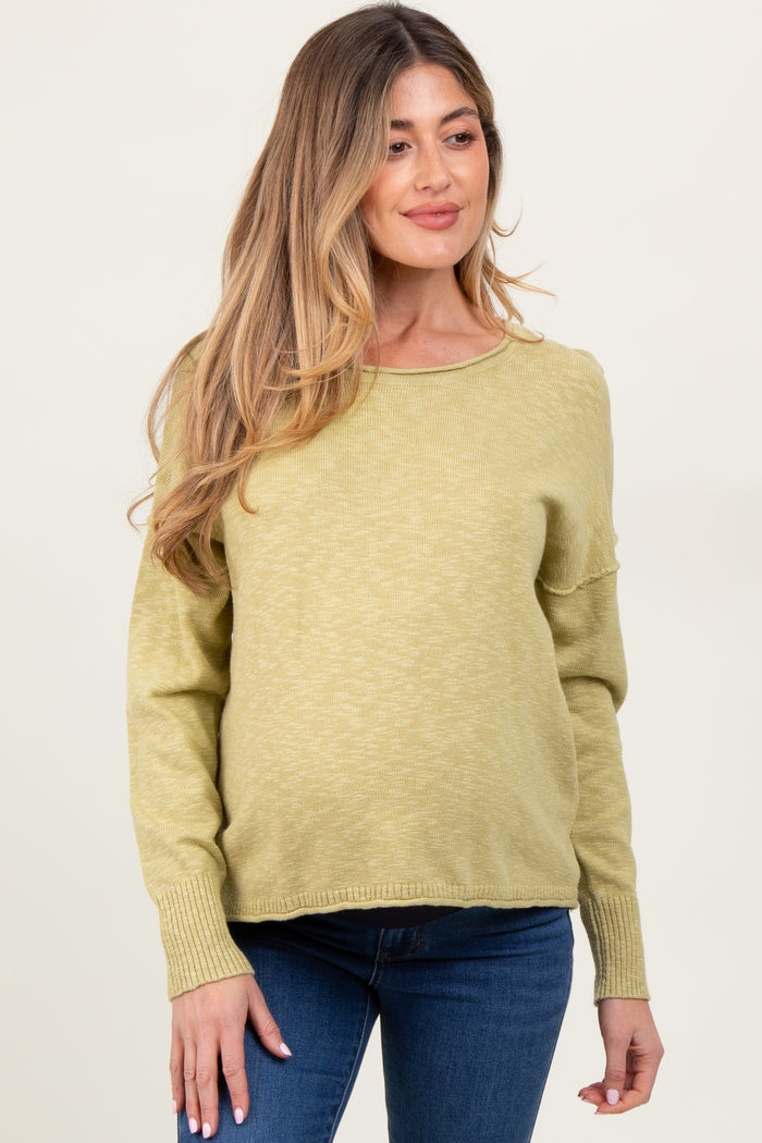 woman wearing a light olive green maternity sweater with long sleeves and relaxed fit, showing baby bump