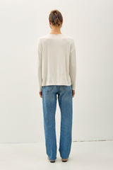 woman wearing a cream long sleeve top and light blue wide leg jeans, photographed from the back