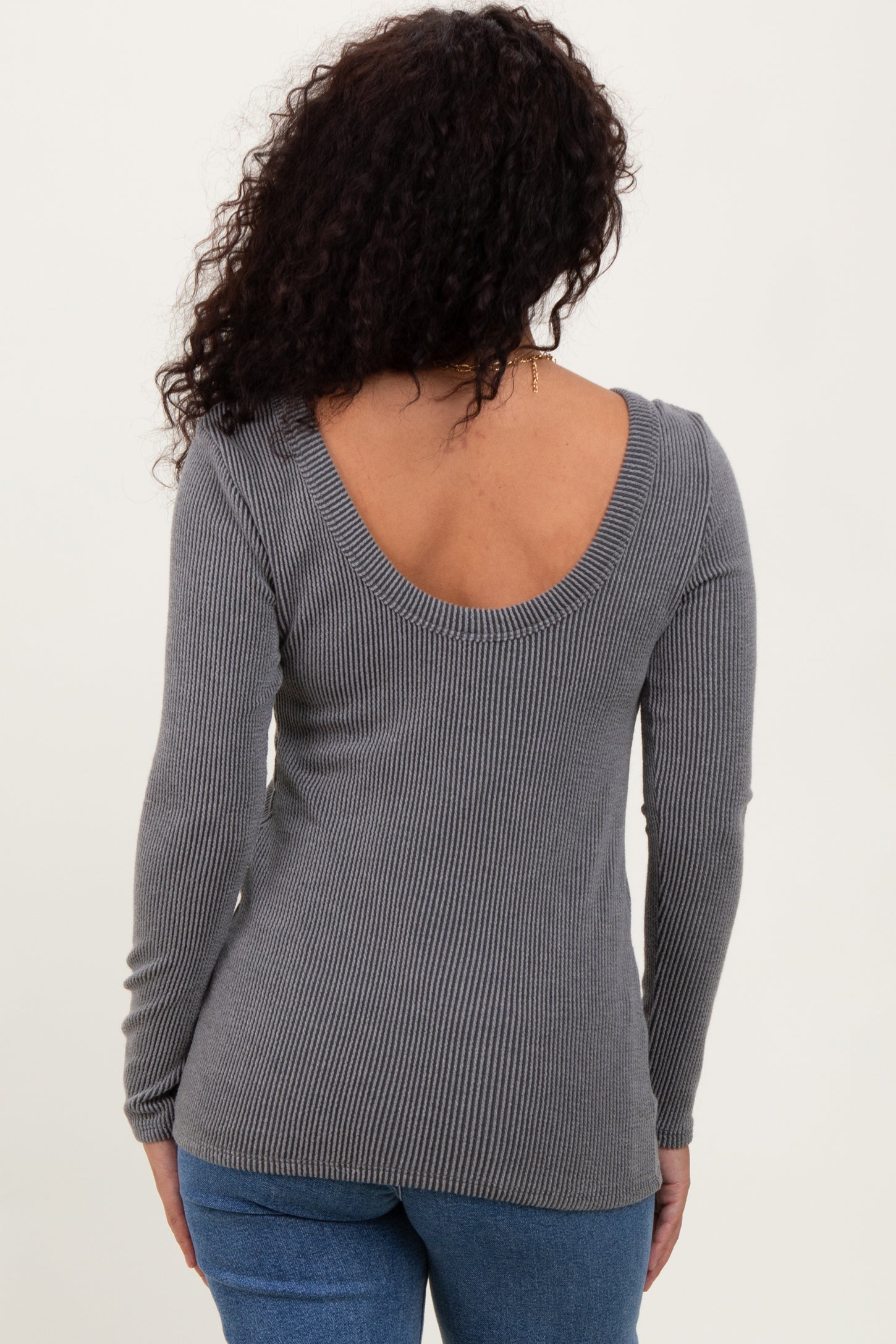 woman wearing a gray ribbed long sleeve top with a scoop back, styled with blue jeans
