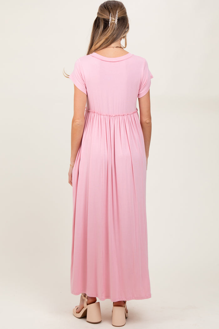 woman wearing a pink maternity maxi dress with short sleeves and an empire waist, showing a baby bump