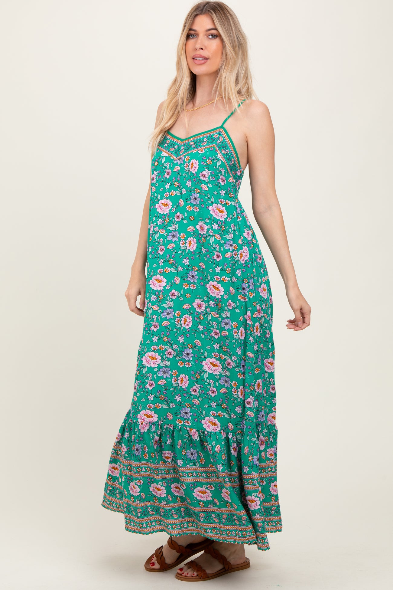 woman wearing a green floral maxi dress with spaghetti straps and a ruffled hem