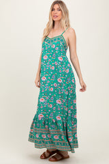 woman wearing a green floral maxi dress with spaghetti straps and a ruffled hem