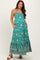 woman wearing a green floral maternity maxi dress with adjustable straps and pockets, showcasing her baby bump