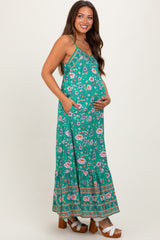 woman wearing a green floral maternity maxi dress and holding her baby bump
